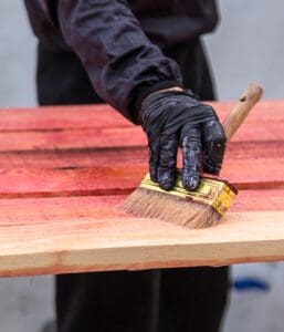 Professional in Atkinson applying fresh stain to restore weathered wooden deck